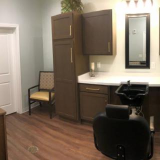 A cozy hair salon interior with a styling station and mirror.
