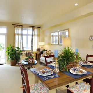 A cozy dining and living area with elegant table settings, greenery, and ample natural light.