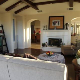 A cozy living room with a fireplace, comfortable seating, and wooden ceiling beams.