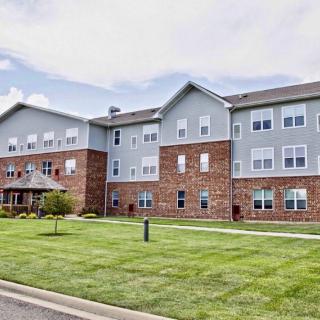 A modern apartment complex with a well-maintained lawn and brick facade.