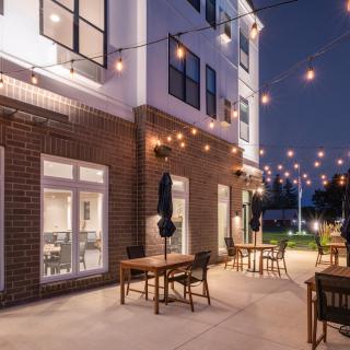 A cozy outdoor patio with string lights and tables set for dining at night.