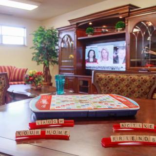 A cozy living room with a Scrabble board set up on the table in front of a television and elegant furniture.