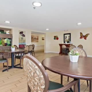 A cozy indoor dining area with tables, chairs, a fish tank, and decorative artwork on the walls.