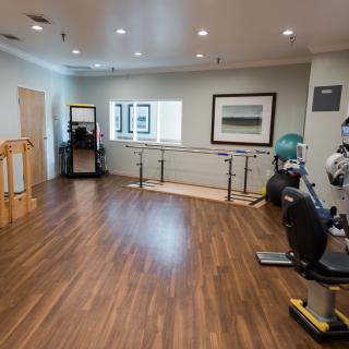 A spacious rehabilitation room equipped with exercise machines and parallel bars.