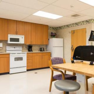 A kitchen area featuring wooden cabinets, a stove, refrigerator, and seating.