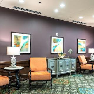 A cozy lobby area featuring orange chairs, decorative art pieces on the wall, and stylish lamps.