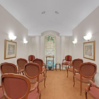 A small, elegantly furnished room with arranged chairs facing a decorative window.