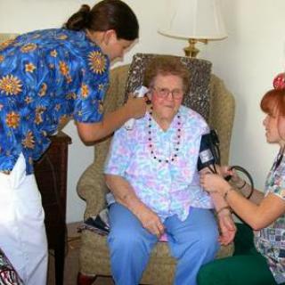 Healthcare professionals conducting a medical examination for an elderly patient in a home setting.