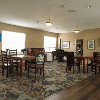 A well-lit dining area with tables and chairs arranged on a patterned carpet.