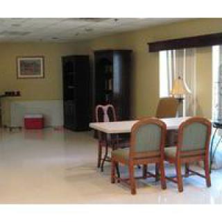 A spacious dining room with a table and chairs, adorned with bookshelves and a window for natural light.