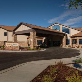 A modern building with a welcoming entrance and landscaped surroundings under a clear sky.