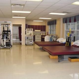 A spacious physical therapy clinic equipped with exercise tables and rehabilitation tools.