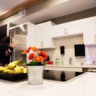 A modern kitchen with white cabinets and a sleek countertop adorned with a potted plant and bananas.