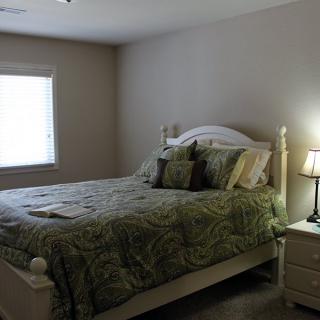 A cozy bedroom with a bed, nightstand, and lamp.