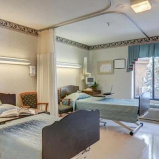 A shared hospital room with two patient beds and medical equipment.