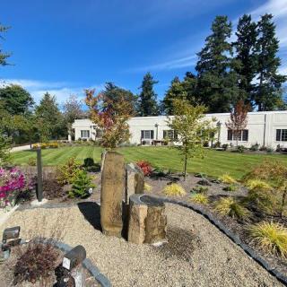 A beautifully landscaped garden with a building in the background under a clear blue sky.
