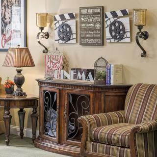 A cozy living room corner with a striped armchair, decorative cabinet, and wall art.