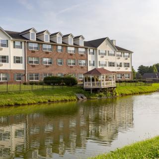 A picturesque building by a tranquil pond with lush greenery surrounding it.