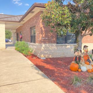 A picturesque autumn scene featuring a brick building with colorful pumpkin decorations along the path.
