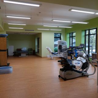 A spacious and well-lit rehabilitation gym with various exercise equipment.