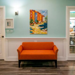 A stylish interior with a bright orange couch beneath a colorful painting.