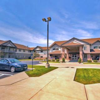 A modern residential building with well-maintained landscaping and a parking lot, captured on a clear day.