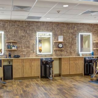 A modern hair salon with brick walls, wooden floors, and illuminated mirrors.
