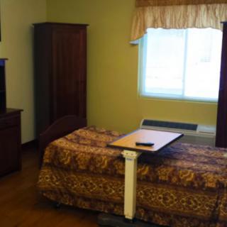 A cozy bedroom with a single bed, a table, and a television.