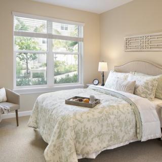 A cozy and well-lit bedroom with elegant decor and a large window.