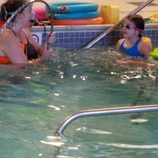 A swimming instructor engages with a child during a lesson in the pool.