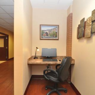 A compact office workspace with a desk, computer, and chair, adorned with artwork on the walls.