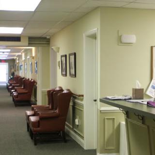A calm and organized waiting area in a healthcare facility featuring comfortable chairs along a well-lit hallway.