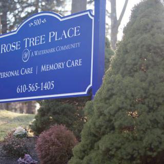 A sign for Rose Tree Place, a care community, surrounded by trees and shrubs.