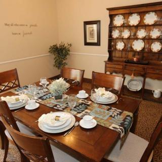A neatly arranged dining room table with elegant dinnerware and a floral centerpiece.