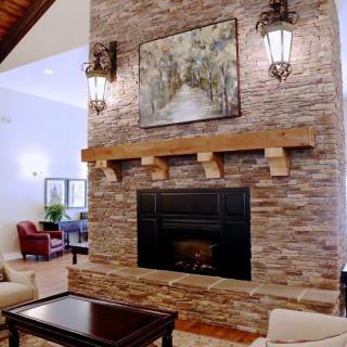 A cozy living room featuring a stone fireplace with artwork and elegant furnishings.