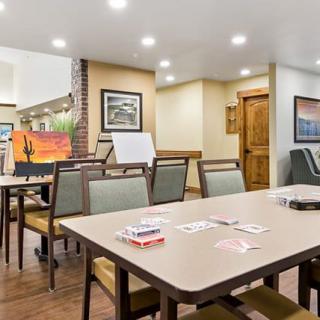 A well-lit meeting room with a conference table, chairs, and a whiteboard, decorated with artwork on the walls.
