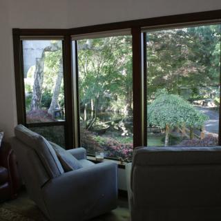 A cozy living room with armchairs facing large windows offering a view of lush greenery.