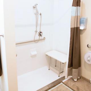 A handicap accessible bathroom with a shower seat and grab bars.