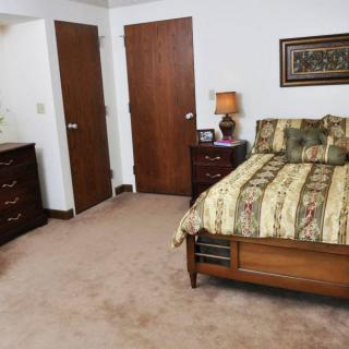 A cozy bedroom with a bed, dresser, and two doors.