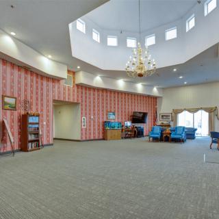 A spacious lobby with comfortable seating, a chandelier, and patterned wallpaper.