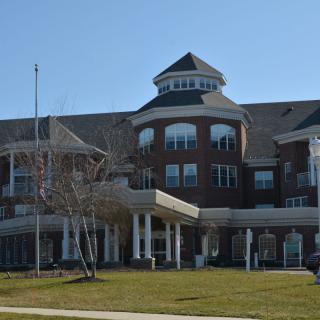 A large brick building with a distinctive roof and numerous windows on a clear day.