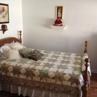 A cozy bedroom with a traditional quilt on the bed and decorative elements on the walls.