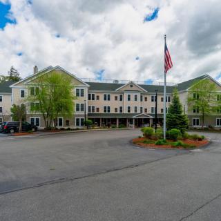 A residential building with a flagpole and landscaped entrance under a cloudy sky.
