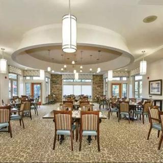 A spacious dining room with elegant lighting and neatly arranged tables and chairs.