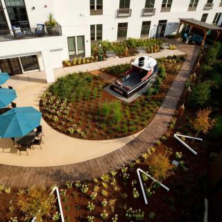 A landscaped garden area with pathways and outdoor seating next to a building exterior.