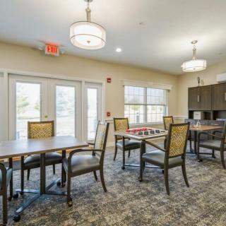 Bright dining area with tables and chairs, illuminated by overhead lighting and natural light from large windows.