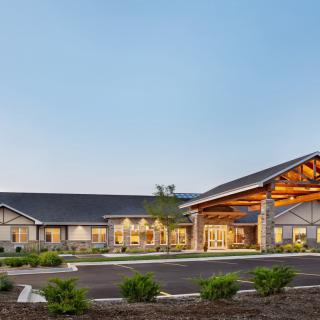 A modern residential building with a spacious driveway and landscaped surroundings at dusk.