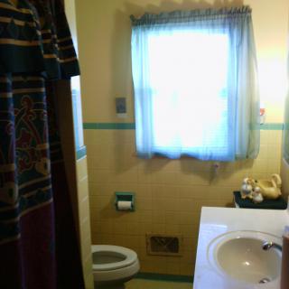 A small bathroom with a window, toilet, and sink.