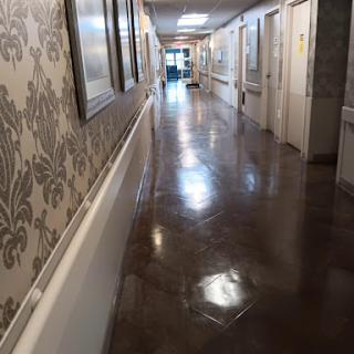 A long hallway with decorative wallpaper and polished floors.
