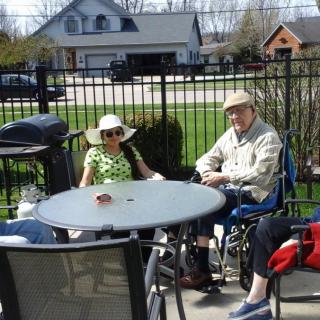 Two people sitting outside on a patio, wearing hats and enjoying the sunny day.